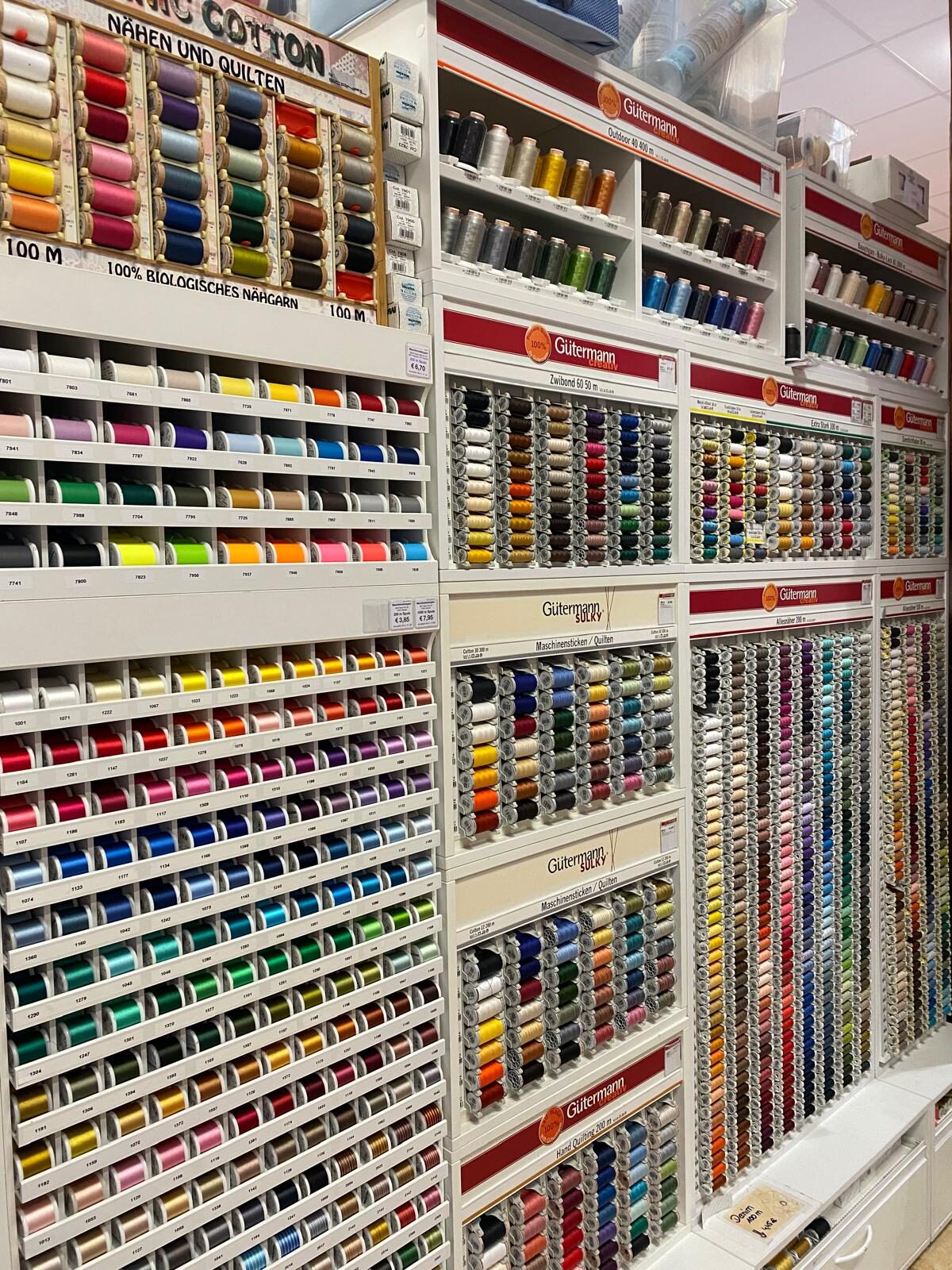Wand mit Nähgarn-Rollen in allen Farben